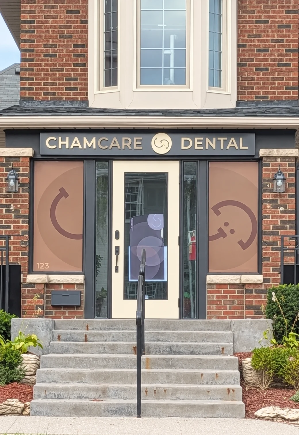 ChamCare Dental’s brick storefront with cream trim, terracotta window panels, and steps to the entrance